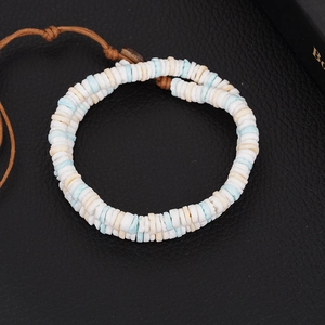 Detail of bohemian bracelet featuring seashell heishi beads and brown waxed cord