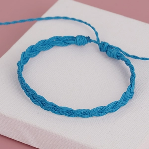 Close-up of bohemian blue hand-woven rope bracelet with adjustable tassel knot on white tile