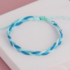 Detail of handmade bohemian braided rope bracelet with blue and white tassels