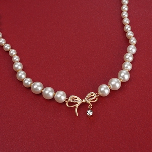 Élégant collier de perles blanches avec pendentif nœud doré étincelant et strass