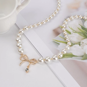 Collier de perles élégant avec pendentif nœud doré et pierre de zircone brillante