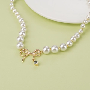 Collier de perles élégant avec pendentif nœud doré et détails en zircons brillants