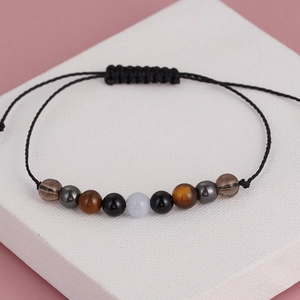 Macro view of handmade woven yoga bracelet with tiger eye and obsidian crystal beads