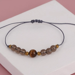 Detailed macro of handmade woven bracelet with tiger eye stone and striped beads