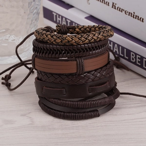 Mehrlagiges geflochtenes Lederarmband-Set in Brauntönen auf einem Holztisch Hintergrund
