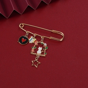 Golden cat safety pin brooch with heart and moon pendants on dark red textured background