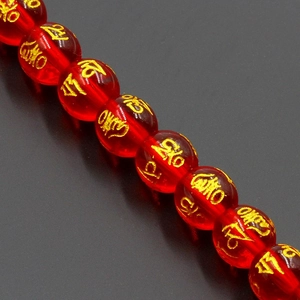 Macro shot of red translucent crystal beads with gold Mantra engraving for DIY jewelry