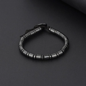 Handgefertigtes Hämatit-Perlenarmband mit schwarzer Kordel auf grauem Hintergrund