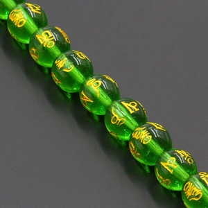 Macro shot of green translucent crystal beads with gold mantra carvings for jewelry DIY