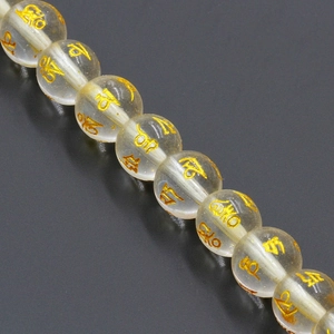 Macro view of transparent natural crystal beads with golden mantra engraving details