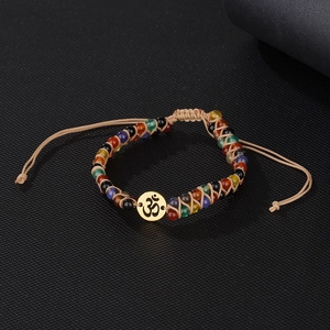 Detailed view of woven multicolored bead bracelet with golden Om symbol charm