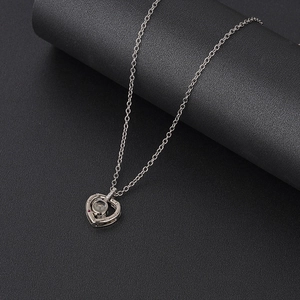 Detailed view of silver heart pendant with center crystal and small red gemstone