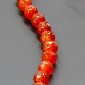 Macro detail of faceted orange red carnelian beads arranged in a curved S-shape line