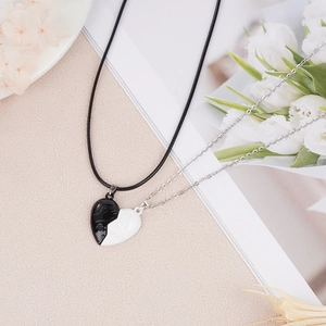 Close-up of magnetic heart necklaces with forever engraving and handshake pattern for couples
