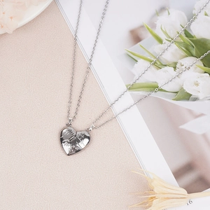 Close-up of polished silver heart-shaped couple necklaces with Forever engraving