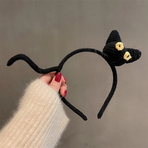 Detail of handmade knitted black cat headband with 3D cat head and cute tail design