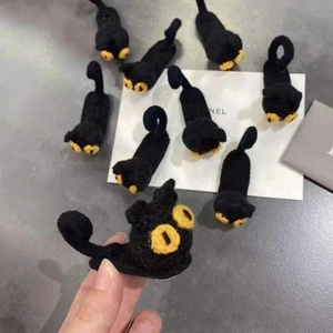 Detailed macro view of handmade knitted black cat hair accessories with yellow eye accents