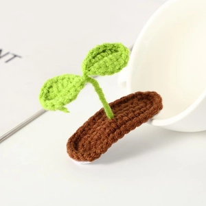 Handmade crochet green sprout hair clip with brown base on a clean white background