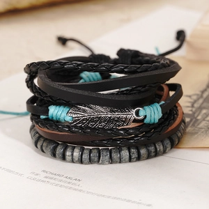 Close-up of vintage multi-layer woven leather bracelets with silver leaf charm detail