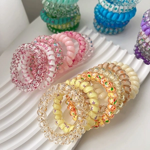 Lot d'élastiques spirales colorés avec paillettes et motifs floraux sur plateau