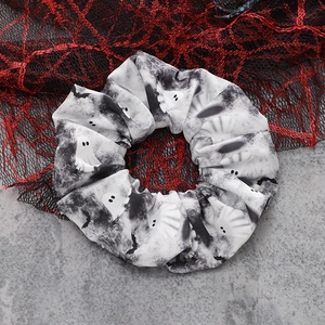 Close-up of Halloween scrunchie with white ghosts and black bats on a spiderweb background