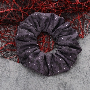 Close-up of purple Halloween scrunchie with bat and spider web patterns for hair
