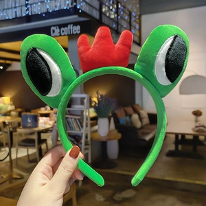 Detail shot of a plush green frog headband with a red crown in a cafe setting