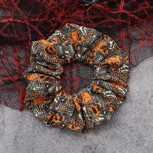Detail of Halloween scrunchie with orange pumpkin and ghost patterns on black mesh
