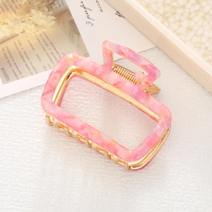 Pink marble acetate hair claw clip with gold metal frame shown on aesthetic background