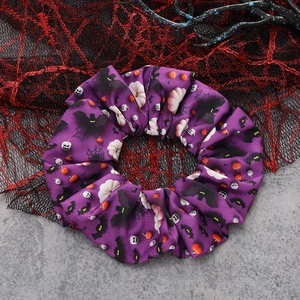 Detail of purple Halloween scrunchie featuring bats and ghosts against a gothic backdrop