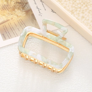 Macro view of a marble-textured green hair claw clip with golden metal inner frame