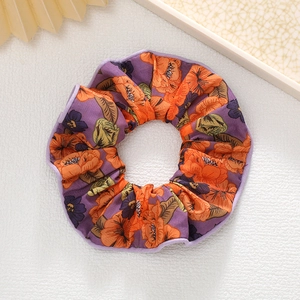 Détail d'un chouchou floral violet avec motifs orange et texture de tissu plissé