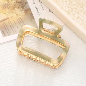 Detail view of sage green acetate shark hair claw clip with a gold-tone metal spring