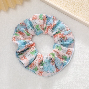 Détail d'un chouchou rose à fleurs avec motif dessin animé sur fond cuir blanc
