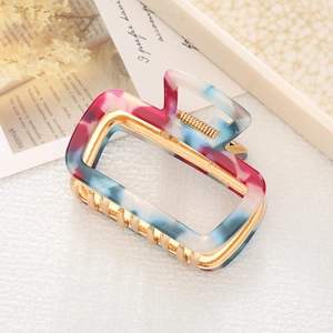 Detail of marble pattern acetate hair claw with golden metal frame and non-slip teeth
