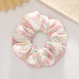 Détail d'un chouchou floral avec des roses roses et une bordure passepoilée élégante