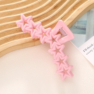 Détail d'une pince à cheveux rose macaron en forme d'étoile sur plateau bois
