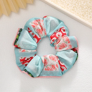 Gros plan d'un chouchou en satin à fleurs avec motifs roses bleues et bords cousus