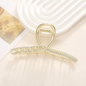 Primer plano de pinza de pelo metálica dorada con pedrería brillante y diseño de cadena