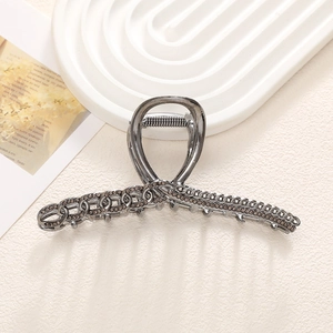Primer plano de pinza de pelo en metal gris plomo con textura de cadena y strass oscuros