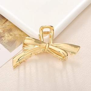 Vista detallada de la elegante pinza para el cabello de metal dorado con forma de lazo
