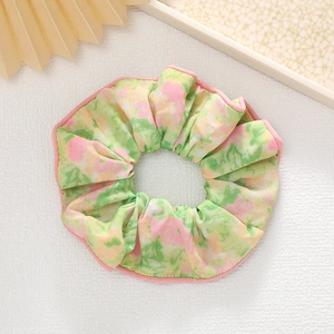 Détail du chouchou floral avec bords froncés roses et texture de tissu élastique