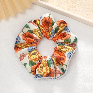 Vue détaillée d'un chouchou floral avec motifs de fleurs oranges sur un support en cuir