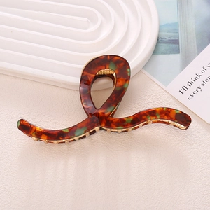 Detail of elegant tortoise shell hair claw clip with gold metal teeth and acetate texture