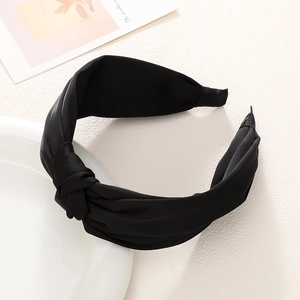 Close-up of black matte twisted headband resting on a white ceramic plate