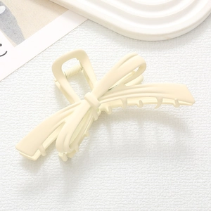 Pince à cheveux nœud crème mate sur un élégant plateau en céramique blanche