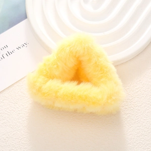 Detailopname van een kleine felgele pluche haarklem in de vorm van een kattenoor