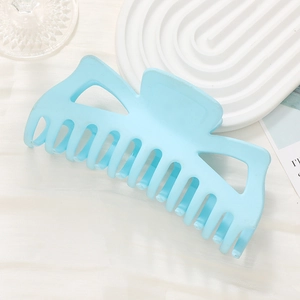 Large matte sky blue shark hair claw clip with hollow design on a white decorative plate