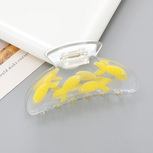 Transparent goldfish claw clip with yellow fish motifs on a minimalist grey background
