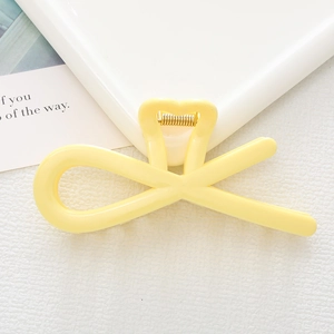 Close-up of a pale yellow hollow heart hair clip with a gold metal spring mechanism